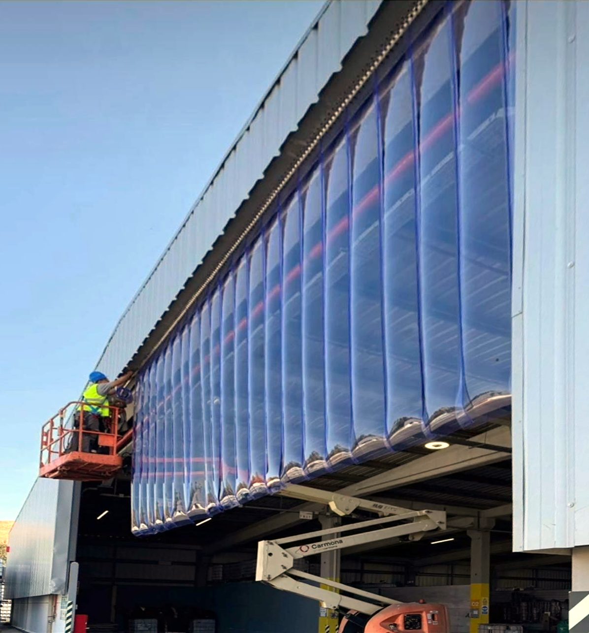 Técnico a instalar uma cortina de lamelas num armazém